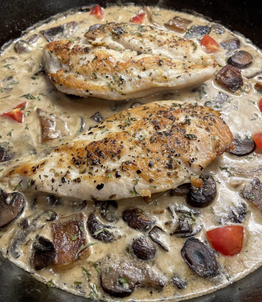 close up of chicken breast in mushroom cream sauce in skillet