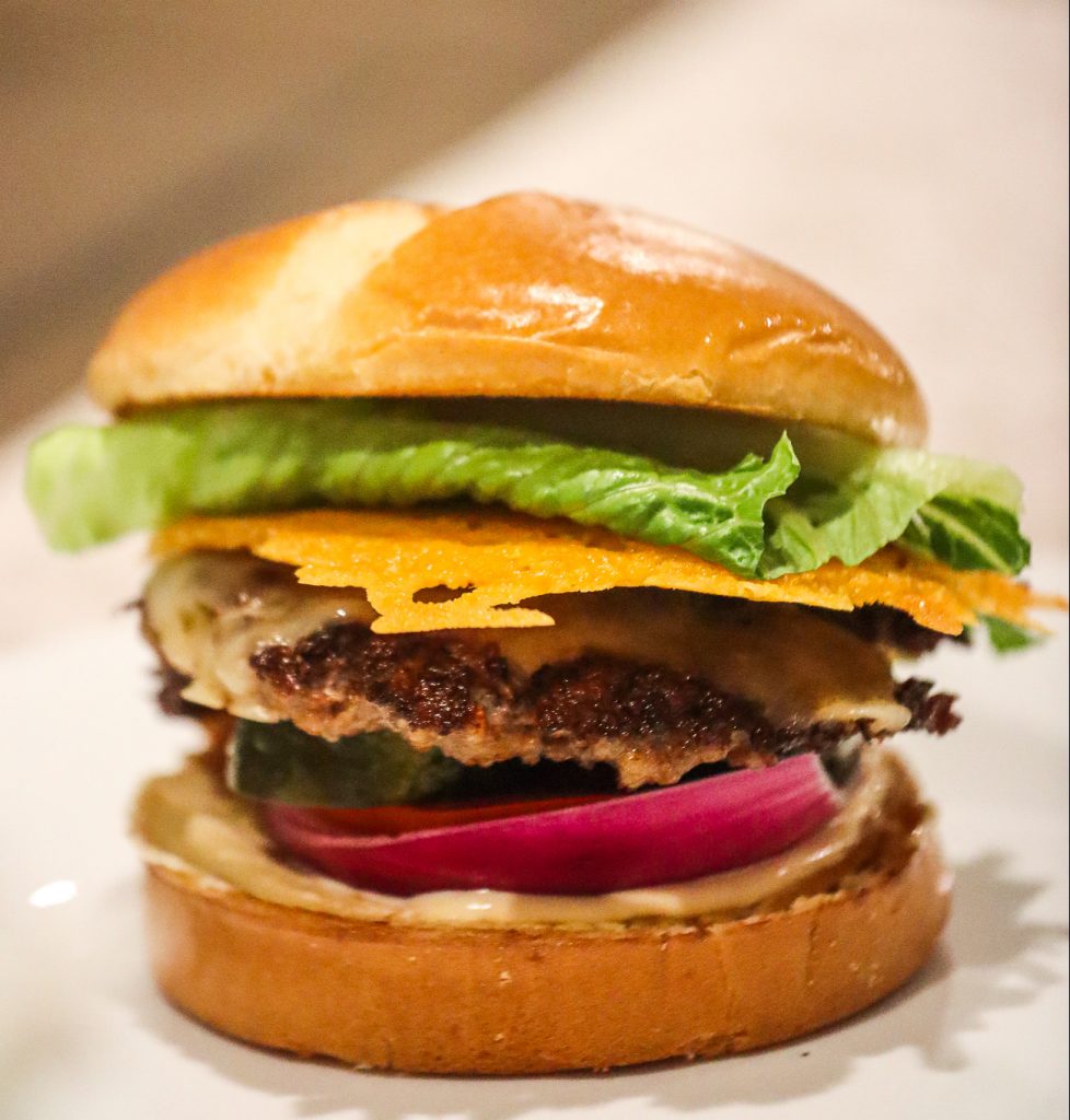 Smash burger on bun with lettuce and cheese on table