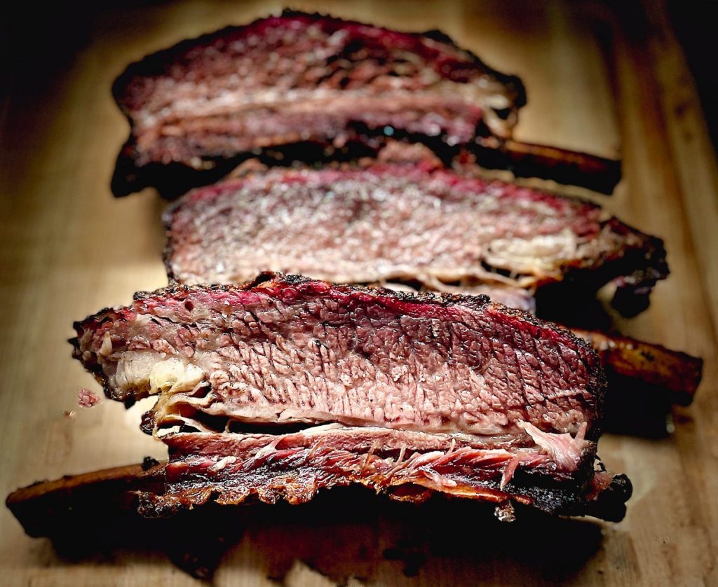 Sliced beef plate ribs in a row on cutting board