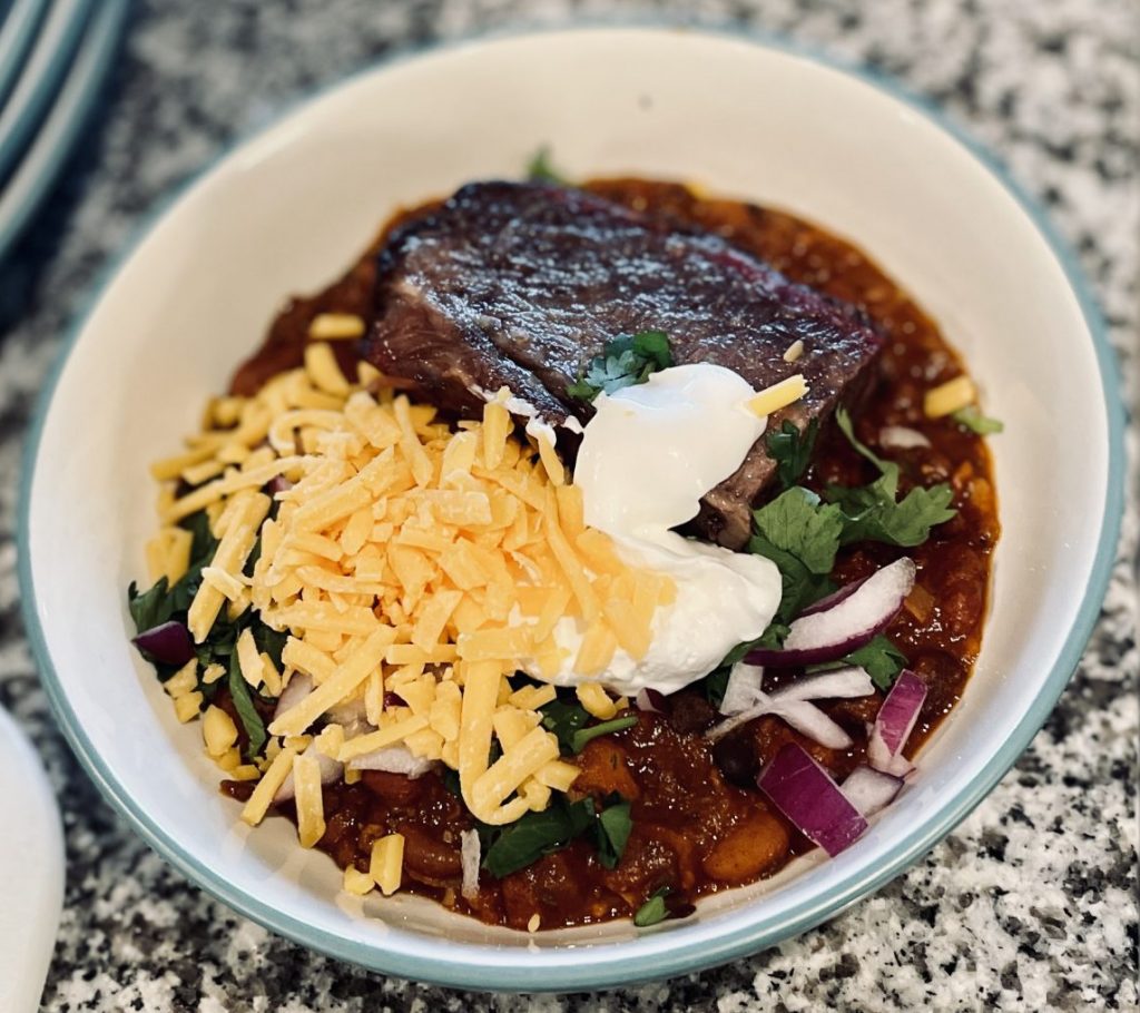 Piece of beef plate ribs in bowl of chili