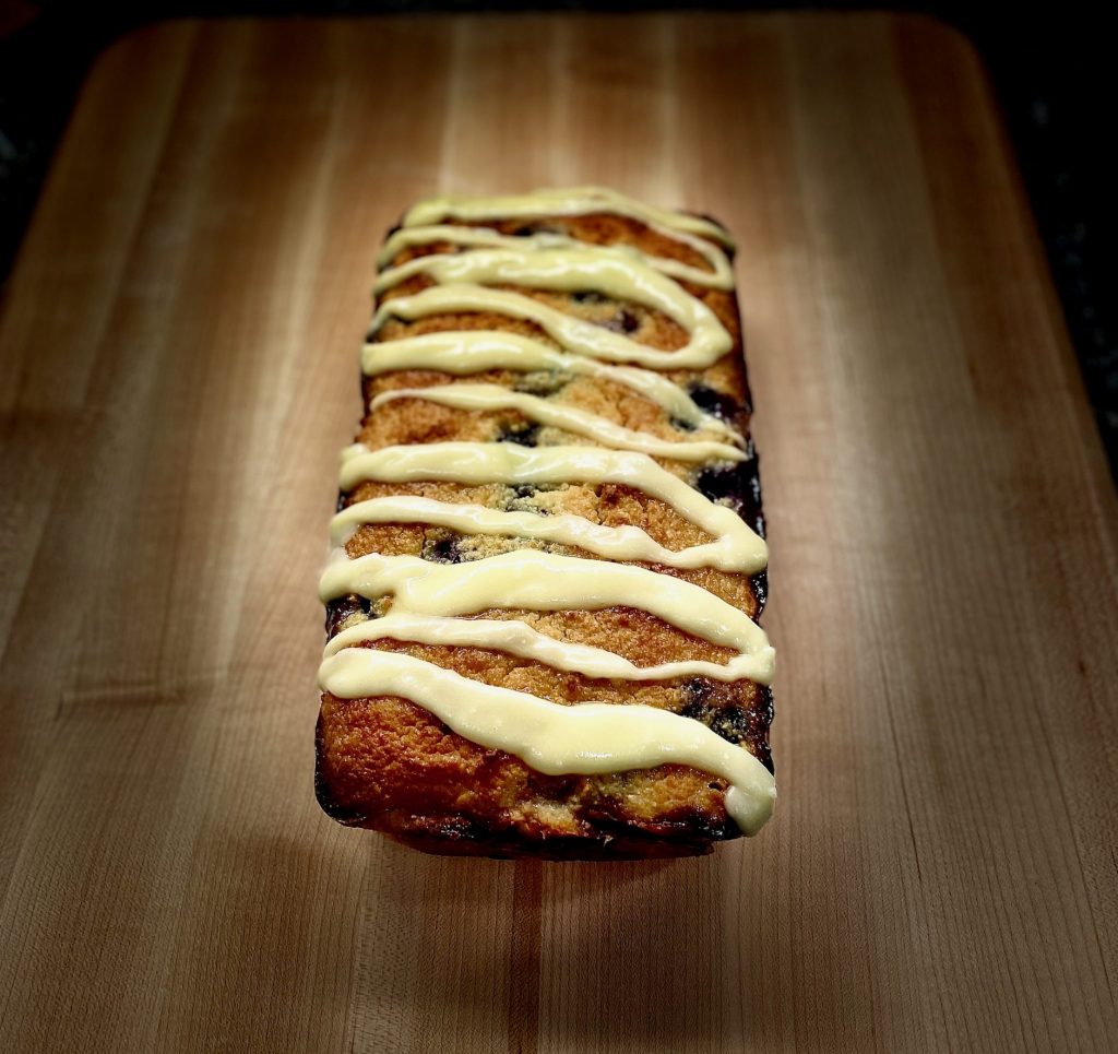 Lemon Blueberry bread with glaze on cutting board