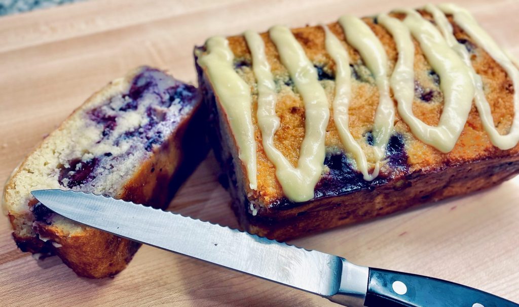 Sliced lemon blueberry bread on cutting board with knife