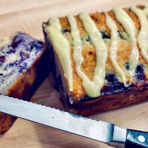 Sliced lemon blueberry bread on cutting board with knife