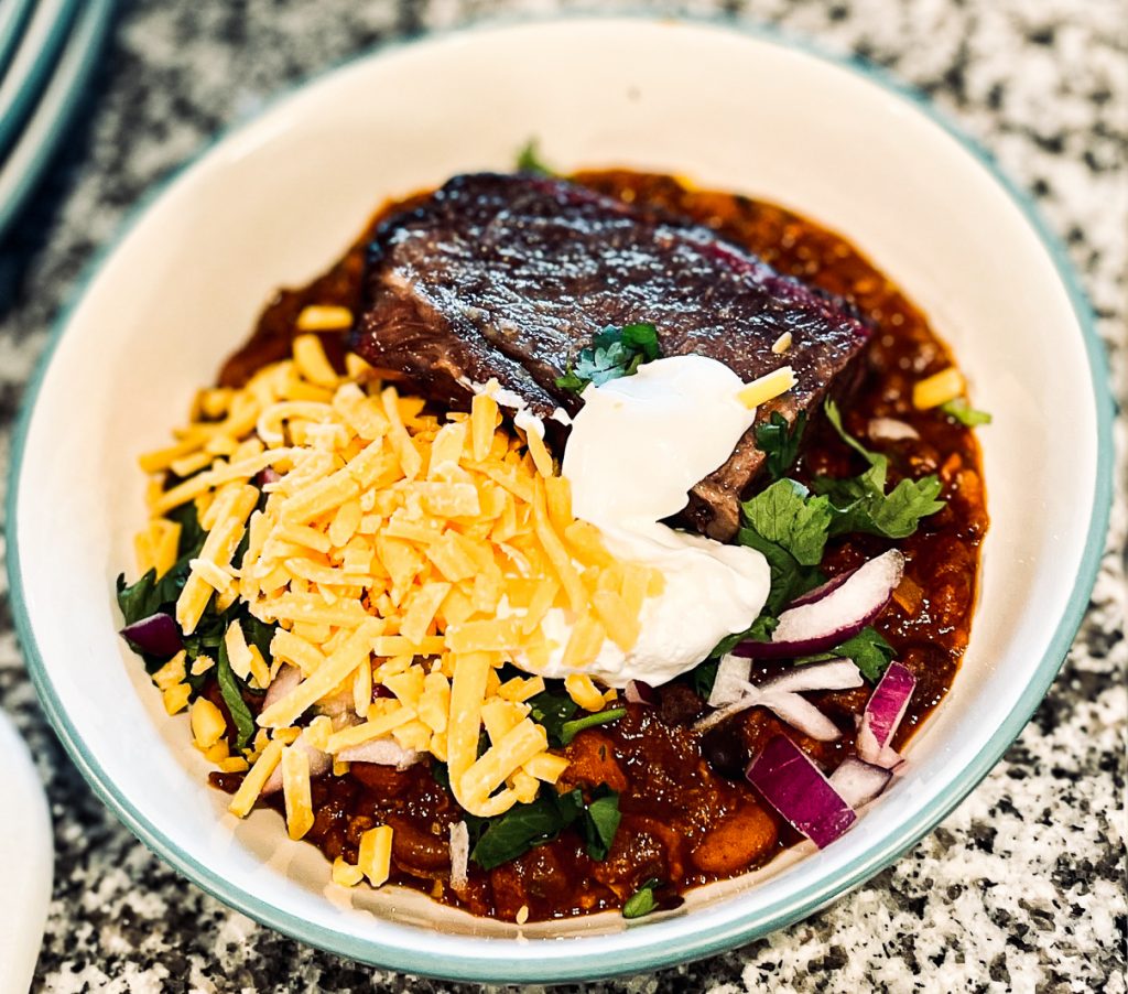 Piece of beef plate ribs in bowl of chili