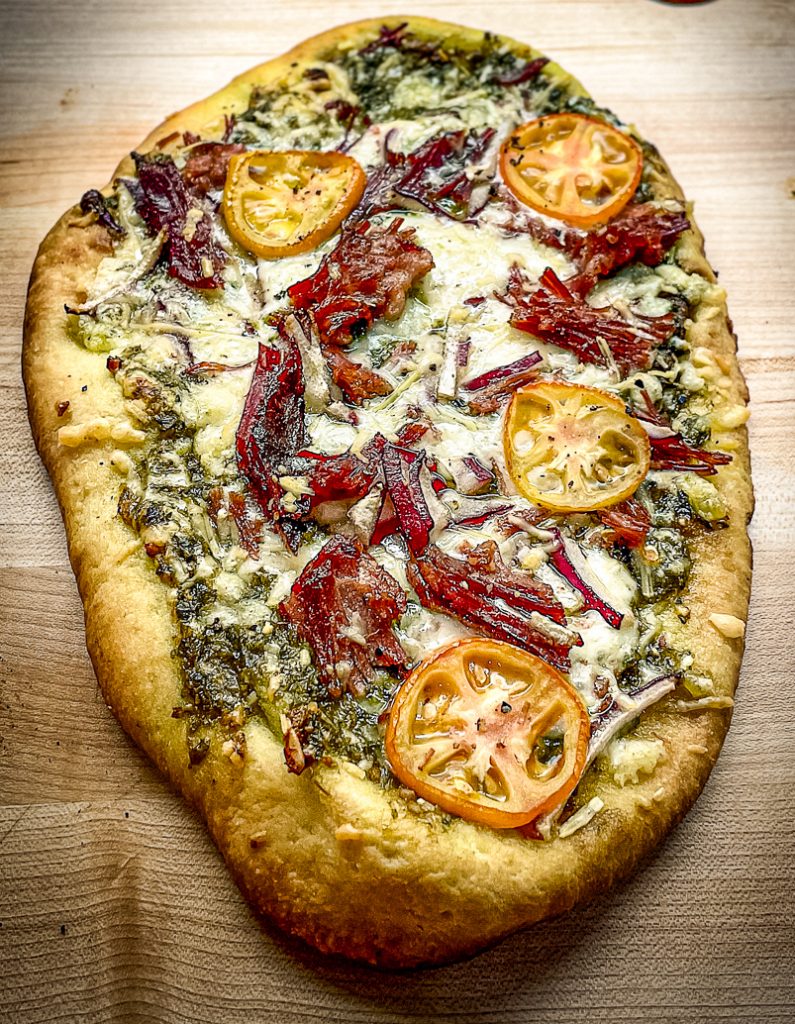 Smoked flatbread with brisket and pesto on cutting board